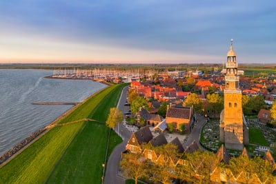 hindeloopen-am-ijsselmeer.jpg Luftaufnahme einer Küstenstadt bei Sonnenuntergang mit einem Kirchturm und Hafen.
