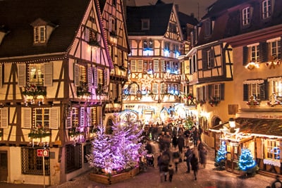 Weihnachtlich beleuchtete Fachwerkhäuser mit Menschenmenge.