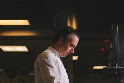 das-excellence-gourmetfestival-10.jpg Koch in weisser Uniform rührt in einem Topf in der Küche.