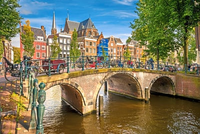 Brücke über einen Kanal in Amsterdam mit Fahrrädern und alten Gebäuden im Hintergrund.
