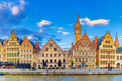Historische Gebäude am Fluss in Gent bei blauem Himmel.
