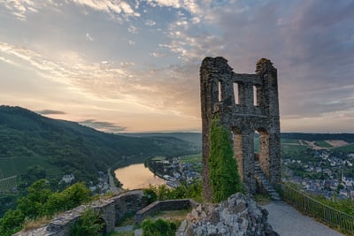 Ruine mit Aussicht auf Fluss und Landschaft bei Sonnenuntergang.