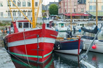 Rote und blaue Boote im Hafen neben einem historischen Gebäude.
