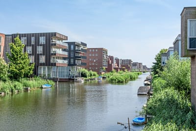Kanal mit modernen Wohngebäuden und kleinen Booten entlang des Ufers.