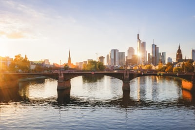 Stadtansicht mit Fluss und Brücke bei Sonnenuntergang.