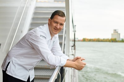 das-excellence-gourmetfestival-10.jpg Mann in weissem Hemd lehnt am Geländer eines Bootes.