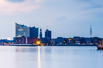 hamburg.jpg Stadtsilhouette bei Dämmerung mit Wasser im Vordergrund.