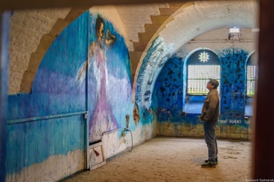 Mann betrachtet Wandgemälde in blauem Raum.
