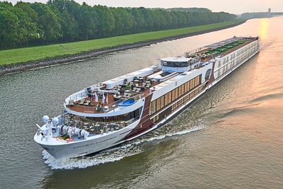 Grosses Flussschiff auf einem ruhigen Fluss bei Sonnenuntergang.