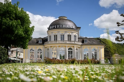 Historisches Gebäude mit Kuppel und Garten im Vordergrund.