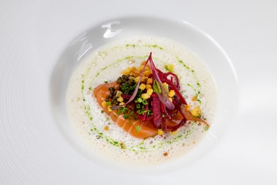 zwei-sternekoeche-viel-genuss-11.jpg Gourmetgericht mit Lachs und Schaum auf einem Teller angerichtet.