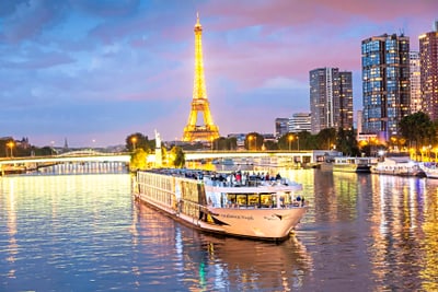 paris.jpg Beleuchtetes Schiff auf der Seine vor Eiffelturm bei Abenddämmerung.