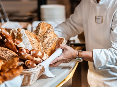Ein Bäcker in weisser Uniform arrangiert Brot in Körben.