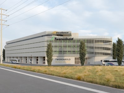 Modernes Gebäude mit Bussen davor und Stromleitungen darüber.