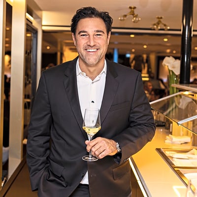 das-excellence-gourmetfestival-1.jpg Mann im Anzug mit Weinglas im Restaurant.