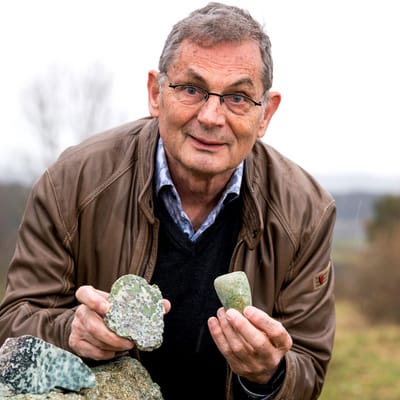 bodenschaetze-am-rhein-1.jpg Älterer Mann im braunen Jacke hält zwei Steine draussen in der Hand.