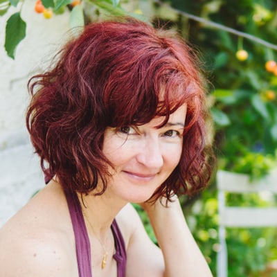 gartenkulturen-am-rhein-1.jpg Frau mit rotem Haar vor grünem Hintergrund.