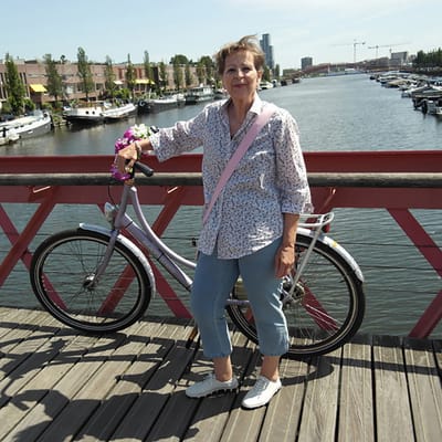 niederlande-land-des-wassers-1.jpg Person mit Fahrrad auf einer Brücke über einem Kanal mit Booten.