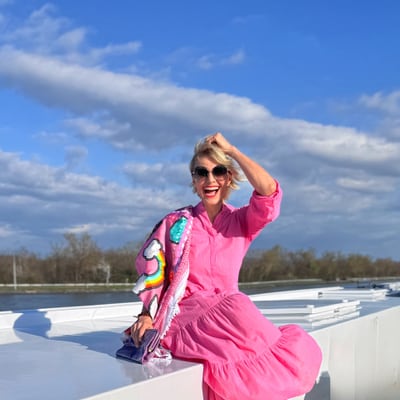 styling-cruise-mit-luisa-rossi-1.jpg Frau in pinkem Kleid sitzt auf weissem Dach bei sonnigem Wetter.