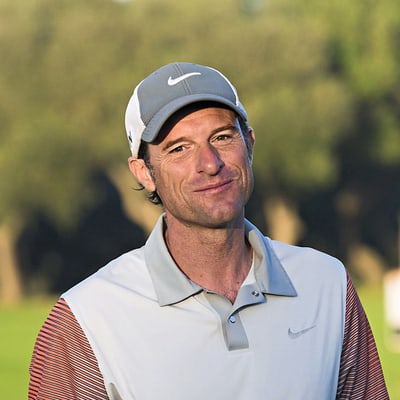 Mann in Golfkleidung auf Golfplatz.