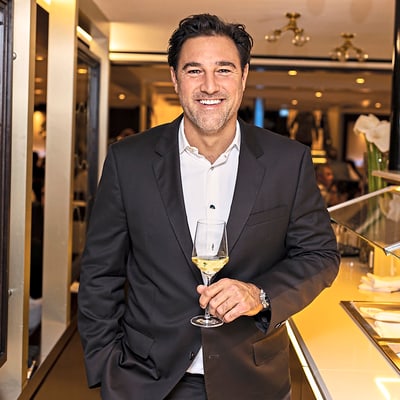 das-excellence-gourmetfestival-1.jpg Mann im Anzug mit Weinglas im Restaurant.