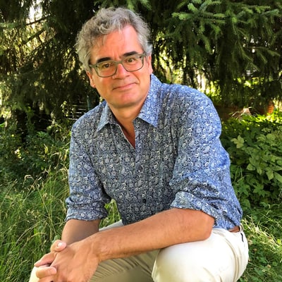 Mann in gemustertem Hemd sitzt im Garten.