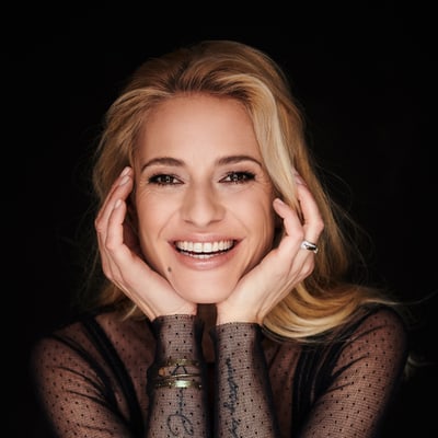 das-excellence-gourmetfestival-1.jpg Lächelnde Frau mit blonder Frisur, schwarze Spitzenbluse.