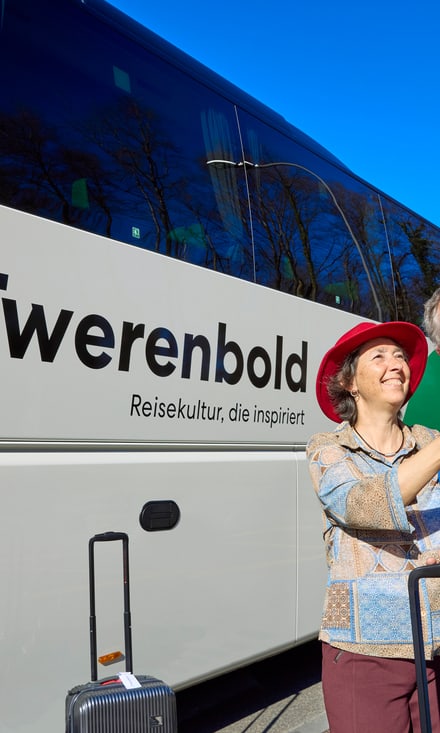 Älteres Paar macht Selfie vor einem Reisebus.