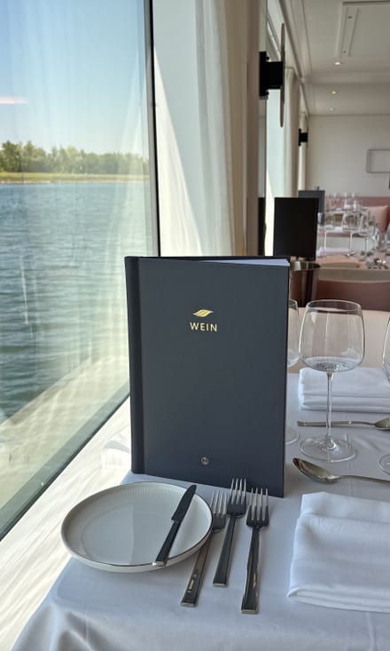 Elegant gedeckter Tisch im Bordrestaurant der Excellence Crown mit Blick durch grosse Fenster auf den Fluss.