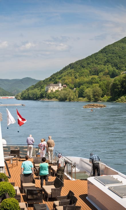 Passagierschiff auf Fluss mit Schloss im Hintergrund.