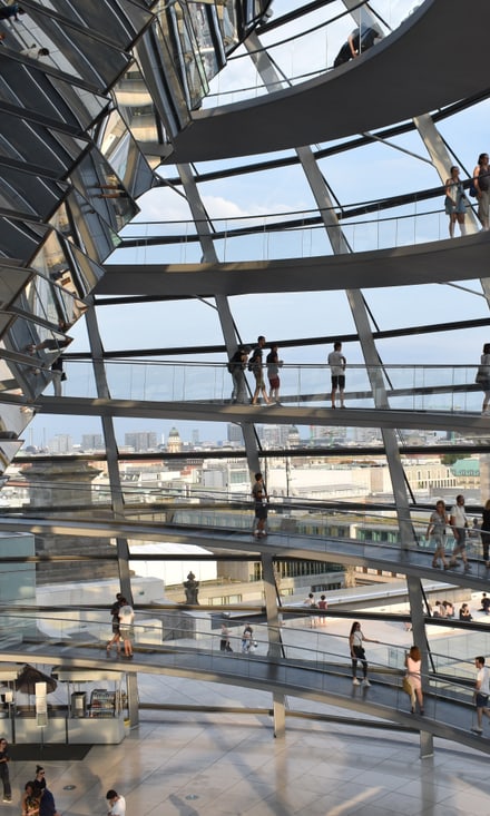Besucher bewegen sich auf spiralförmigen Rampen in der gläsernen Kuppel des Berliner Reichstagsgebäudes.
