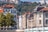 Stadtansicht mit Fluss, Brücke und Hügel mit Kirche im Hintergrund.