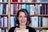 Person hält ein Buch vor einem Bücherregal.