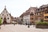 Historischer Platz mit alten Fachwerkhäusern und Springbrunnen.