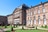 Historisches Gebäude mit gepflegtem Garten und Springbrunnen.