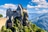 Burg auf einem Hügel mit Wald und Bergen im Hintergrund.