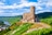 Burg auf Hügel mit Fluss und Weinbergen im Hintergrund.