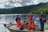 Menschen in orangefarbenen Overalls auf einem Boot auf einem See.