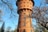 Historischer Wasserturm im Frühling mit blühenden Bäumen.