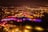 Drohnenansicht einer beleuchteten Festung und Stadt bei Nacht.