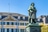 Statue vor historischem Gebäude mit gelben und weissen Fassaden.