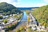 Panoramablick auf Fluss und Stadt zwischen bewaldeten Hügeln.
