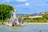 Prunkvoller Springbrunnen im Park mit Schloss und blauem Himmel.