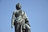 Statue einer historischen Figur vor blauem Himmel.