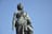 Statue einer historischen Figur vor blauem Himmel.