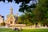 Menschen sitzen auf Rasen vor russisch-orthodoxer Kapelle in sonnigem Park.