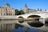 Historische Gebäude und Brücke über einem Fluss an einem sonnigen Tag.