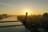 Sonnenuntergang hinter einer modernen Brücke über einem Fluss in einer Stadt.