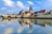 Flussblick auf mittelalterliche Stadt mit Brücke und Kirchtürmen.