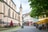 Stadtstrasse mit alten Gebäuden, Sitzgelegenheiten im Freien und Sonnenschirmen.